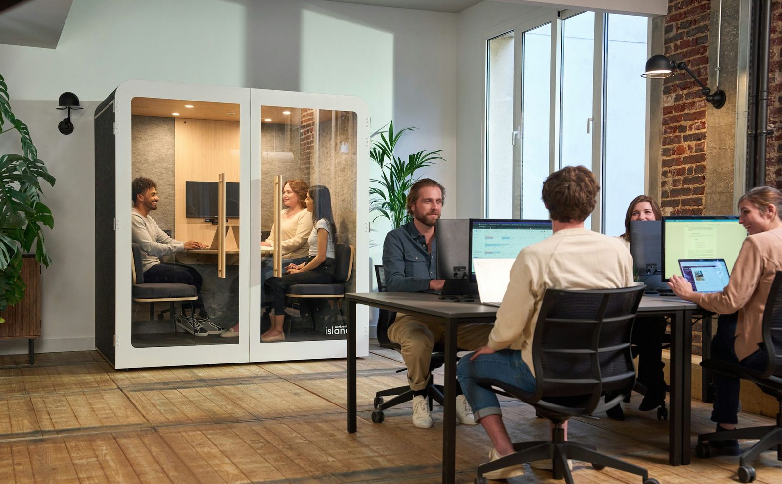 Office floor with an acoustic booth and shared workstations.