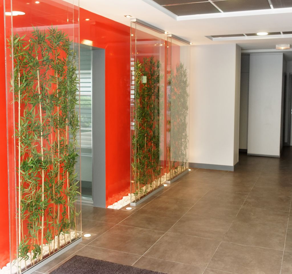 Reception: red lacquered wall, bamboo in lit vertical glass cases, large-format stoneware floor tiles.
